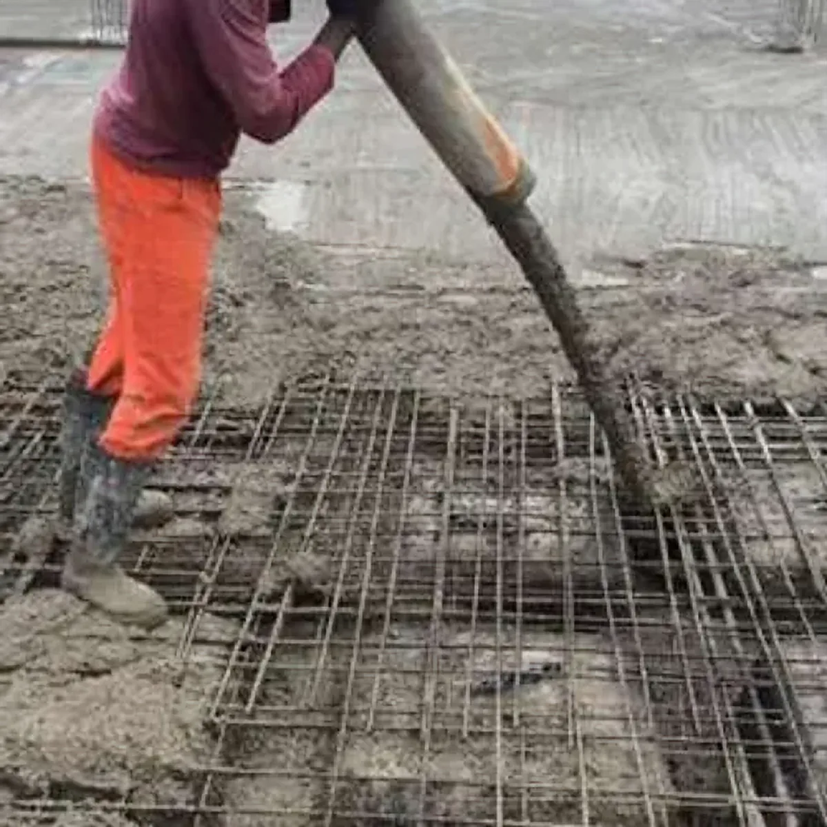 Operário direcionando mangote de concreto sobre armadura